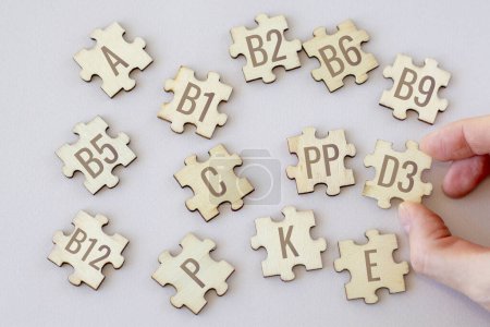 Foto de Set of puzzles with 13 essential vitamins with inscriptions on a beige background. Complex A, B1-B12, C, D3, E, K, P, PP - Imagen libre de derechos