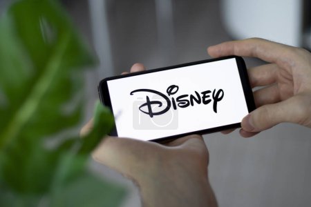 Téléchargez les photos : IRPEN, UKRAINE - JANUARY 20 20223, Closeup of smartphone screen Walt Disney Company logo lettering with in mans hands, Illustrative Editorial - en image libre de droit