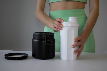 A slender young woman prepares a sports shake for a workout