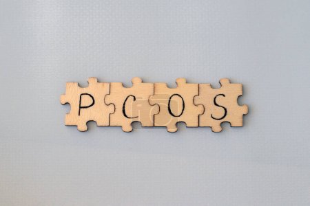 Polyzystisches Eierstocksyndrom. Handschrift PCOS auf Holzpuzzles auf blauem Hintergrund.