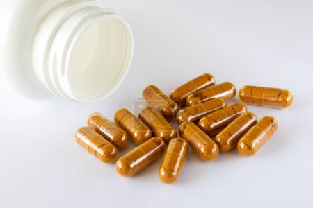Vitamin Curcumin, Kurkuma in Kapseln auf weißem Hintergrund neben dem liegenden Glas mit Nahrungsergänzungsmitteln. Pillen und Medikamente.