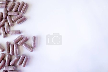 Foto de Cápsulas rosadas con aditivos sobre fondo blanco. Comprimidos y medicamentos. Vitaminas, minerales, extractos de plantas y otras sustancias útiles. Vista superior, espacio de copia. - Imagen libre de derechos