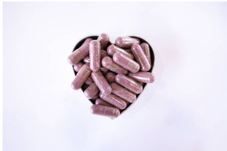 Photo for Pink capsules with supplements on a white background in the shape of a heart. Tablets and medications. - Royalty Free Image