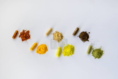 Foto de Opened and whole capsules of dietary supplements on a white background. Various tablets and vitamins. From top right to left: curcumin, Coenzyme q10, vitamin C, quercetin, ant tree bark, vitgrass. - Imagen libre de derechos