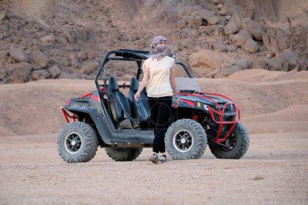 Photo for Young woman was riding a buggy. Walks away from him in the desert and looks away - Royalty Free Image