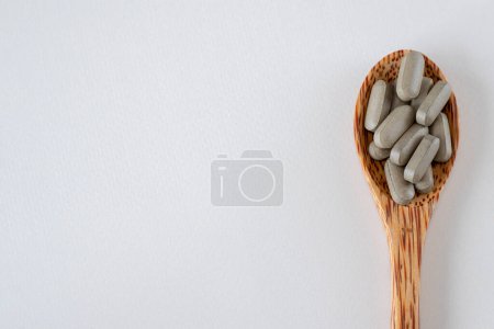 Photo for Brown long pills or supplements in a wooden spoon, top view. Copy space for text - Royalty Free Image
