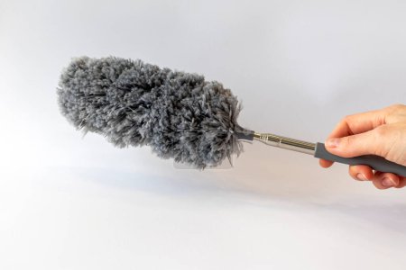 Dust collector brush gray in a womans hand on a white background.