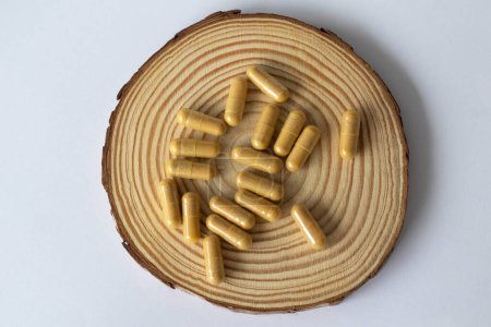Foto de Medicamentos herbarios y suplementos de salud. Cápsulas de polvo marrón sobre una base de madera. - Imagen libre de derechos