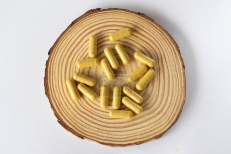 Foto de Cápsulas amarillas sobre fondo de madera y blanco. Medicamentos o pastillas para la salud renal - Imagen libre de derechos