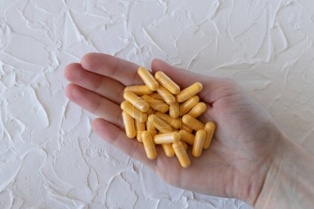 Foto de Medicamentos o suplementos amarillos, cápsulas de coenzima Q10 en una mano de mujer. - Imagen libre de derechos