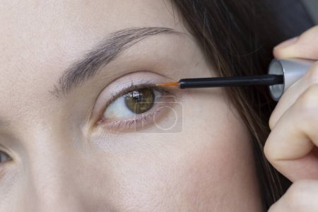 Kosmetisches Wimpernwachsöl wird in Nahaufnahme auf die Wimpernwachslinie aufgetragen. Wimpernbehandlung.