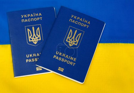 Reisepass der Ukraine auf dem Hintergrund der ukrainischen Flagge. Migration des ukrainischen Volkes im Zusammenhang mit dem Einmarsch russischer Truppen.
