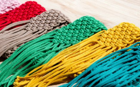 Photo for Small handbags knitted with macrame technique. Multicolored mobile phone bags on a wooden background. - Royalty Free Image