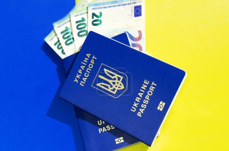 Téléchargez les photos : Passeports de l'Ukraine et monnaie euro sur le fond du drapeau ukrainien. Assistance financière au peuple ukrainien de l'Union européenne dans le cadre de l'invasion des troupes russes. - en image libre de droit