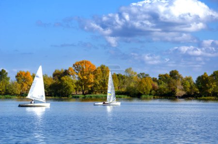 Photo for Two yachts on the Dnieper River against the backdrop of an autumn landscape. Ukraine, Kyiv, Obolonsky district near a residential area, wild nature - Royalty Free Image