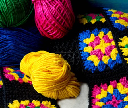 Colorful cotton granny square. Crochet texture close-up, hooks and balls of thread.