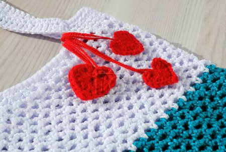 Women's bag made of polyester cord is decorated with red hearts. String bag for groceries on a wooden background.