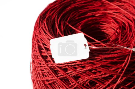 Red raffia on a white background. Close-up of a skein of raffia. Crochet. Eco-friendly handmade material.