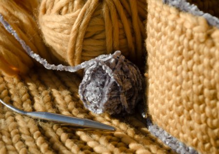 Panier tricoté en fil jaune. Il y a une boule de fil et des aiguilles à tricoter sur la table. Fait à la main.