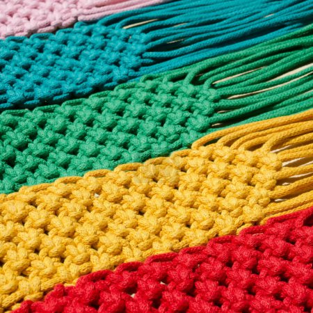 Macrame-Technik, ein quadratischer Knoten aus mehrfarbigen Fäden. Farbige Makramabänder in den Farben blau, gelb, rot, beige, grün und rosa.