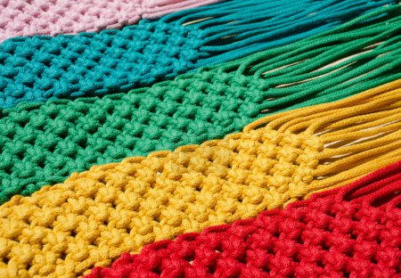 Macrame-Technik, ein quadratischer Knoten aus mehrfarbigen Fäden. Farbige Makramabänder in den Farben blau, gelb, rot, beige, grün und rosa.