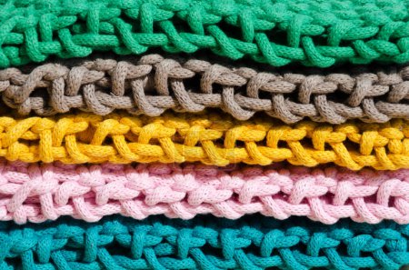 Texture of macrame weaving close-up. Knots made of bright cotton cords. Multi-colored bags for mobile phones.