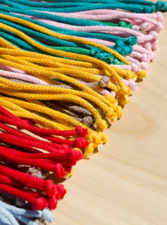 Macrame technique, a square knot of multi-colored threads. Colored macrame stripes in blue, yellow, red, beige, green and pink colors.