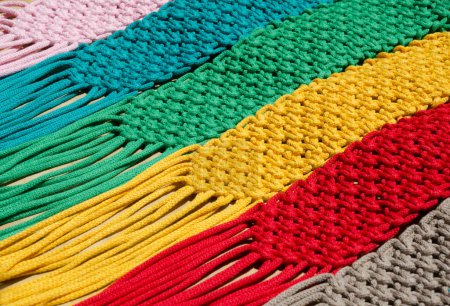 Macrame technique, a square knot of multi-colored threads. Colored macrame stripes in blue, yellow, red, beige, green and pink colors.
