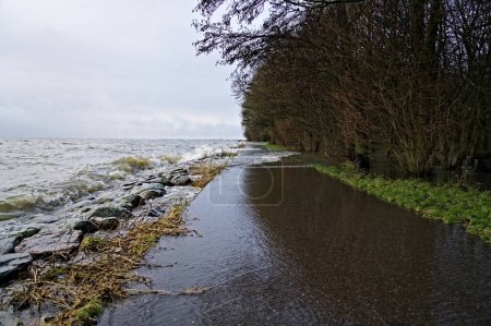 Alto nivel de agua debido a las fuertes lluvias y tormentas, las olas del lago Markermeer se estrellan sobre el dique de piedra y el sendero e inundan la ciudad del parque de Hoorn, Países Bajos
