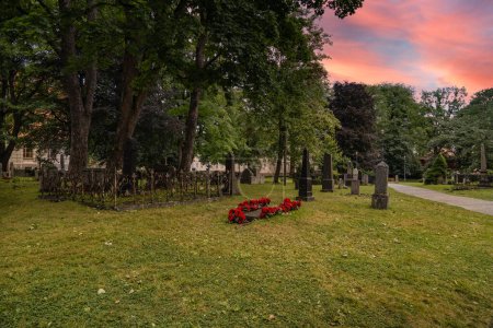 Dusk at Nidaros Cathedral Graveyard in Trondheim, Norway. A serene evening at the Cathedral burial ground with a sunset sky casting warm hues over the historic site