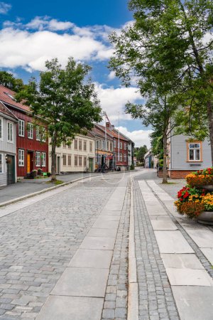 Traditional colorful houses line the cobblestone street of Ovre Bakklandet in Trondheim, Norway on a sunny summer day, tourist travel destination.