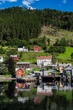Das ruhige Wasser des Stangvikfjords spiegelt das malerische Dorf Kvanne und den Fährhafen unter blauem Sommerhimmel wider, More og Romsdal, Norwegen