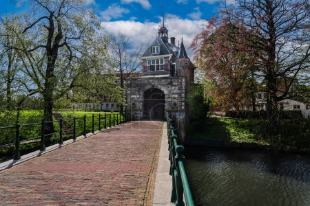 Vista de la arquitectura renacentista Puerta de Oosterpoort desde la edad de oro y el puente contiguo en la ciudad holandesa de Hoorn bajo un cielo de nubes azules.