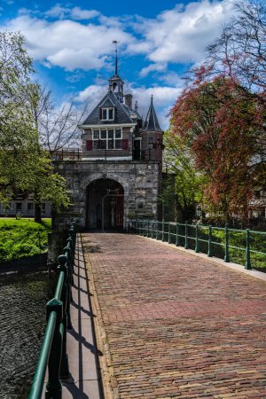 Vista de la arquitectura renacentista Puerta de la ciudad de Oosterpoort desde la edad de oro y el puente contiguo en la ciudad holandesa de Hoorn bajo un cielo de nubes azules en primavera