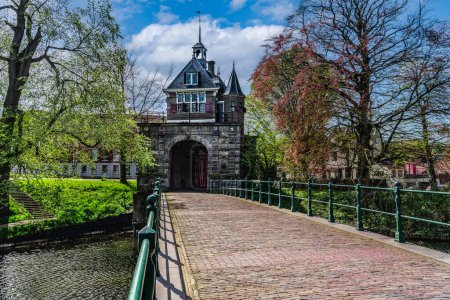 Vista de la arquitectura renacentista Puerta de Oosterpoort desde la edad de oro y el puente contiguo en la ciudad holandesa de Hoorn bajo un cielo de nubes azules en primavera