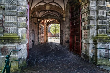 Curved cobblestone path leading through the mannerism architectural style Oosterpoort city gate, a 17th century gate in Hoorn North Holland, Netherlands.