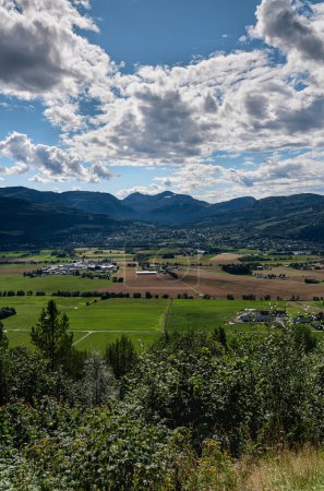 Sommerpracht über Sylte und Surnadal: Ein Blick aus der Vogelperspektive auf norwegisches Ackerland. Grüne Felder und ländliche Häuser eingebettet in die majestätische Berglandschaft Norwegens