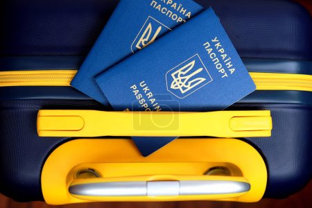 Foto de 2 pasaportes Ucrania con inscripción en ucraniano Pasaporte de Ucrania se encuentran en la maleta de color amarillo-azul en color de la bandera de Ucrania en la frontera. Concepto de viaje, refugiados, turismo, emigración - Imagen libre de derechos