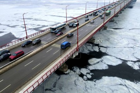 Foto de Muchos coches conducen por el puente del río en invierno. Atasco de tráfico, contaminación del aire, smog en la carretera, carretera. Puente en Dnipro Ucrania, vista aérea del dron - Imagen libre de derechos