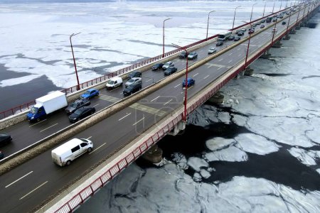 Foto de Atasco de tráfico, contaminación del aire, smog en la carretera, carretera. Muchos coches conducen por el puente del río en invierno. Puente en Dnipro Ucrania, vista aérea del dron - Imagen libre de derechos