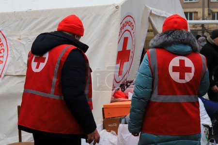 Téléchargez les photos : Dnipro Ukraine 2023-01-14. Red Cross volunteers help wounded near destroyed house after Russian missile attack. Red cross sign on uniform of paramedic - en image libre de droit