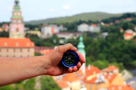Téléchargez les photos : Tourist holds compass against medieval town Cesky Krumlov in Czech Republic. Travel, vacation and hiking. Summer, spring holidays, recreation for people - elderly, adults and children. - en image libre de droit