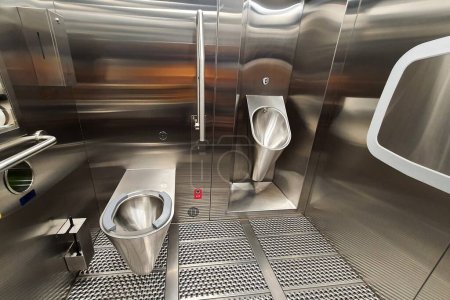 Sanitäre Metall-Urinal und WC-Schüssel im öffentlichen Badezimmer mit hygienischen automatischen Wasserspülung. Urinal mit Urinsensor. Induktive Toilettenspülung. WC, Moderne Sanitär