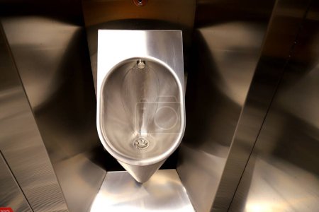 Téléchargez les photos : Urinoir métallique hygiénique, cuvette de toilette dans la salle de bain publique avec chasse d'eau électronique hygiénique et économique en eau. Urinoir avec capteur d'urine. Toilettes à chasse d'eau inductive. WC, plomberie moderne - en image libre de droit