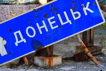 Foto de Guerra de Rusia contra Ucrania, guerra de Ucrania. Señal de tráfico con inscripción en ucraniano Donetsk, perforado por balas y roto, Destrucción en Ucrania - Imagen libre de derechos