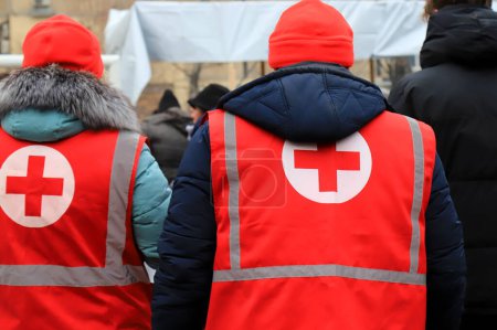 Téléchargez les photos : Des volontaires de la Croix-Rouge distribuent de l'aide humanitaire, aident les blessés près des maisons détruites après l'attaque à la roquette russe. Signature de la Croix-Rouge sur l'uniforme médical. Guerre ukrainienne Dnipro Ukraine, 2023-01-15 - en image libre de droit