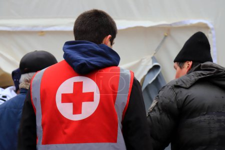 Téléchargez les photos : Des volontaires de la Croix-Rouge distribuent de l'aide humanitaire, aident les blessés près des maisons détruites après l'attaque à la roquette russe. Signature de la Croix-Rouge sur l'uniforme médical. Guerre ukrainienne Dnipro Ukraine, 2023-01-15 - en image libre de droit