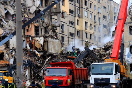 Foto de Russian missile strike destroyed residential building. Rescuers are looking for people under rubble of house, rescue equipment, fire. Russian war in Ukraine, Dnipro, 2022-01-15 - Imagen libre de derechos