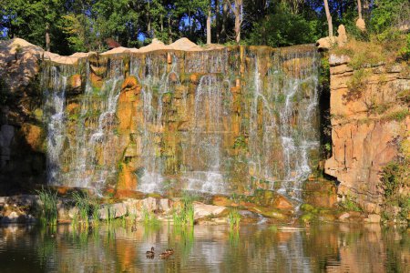 Malowniczy wodospad płynie wiosną wśród dużych kamieni w krajobrazie. Piękny ukraiński wodospad, park Sofiyivka, Uman, Ukraina. Góry i przyroda latem, jesienią