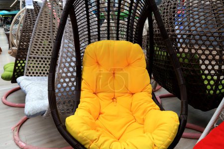 Téléchargez les photos : Chaise cocon rotin, salon de jardin avec coussin jaune en magasin. Beau mobilier moderne en osier à la mode, canapé, fauteuil à bascule cocon pour l'intérieur, détente - en image libre de droit
